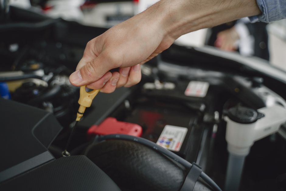 Hand checking oil dipstick in a car engine bay for maintenance and diagnostics.